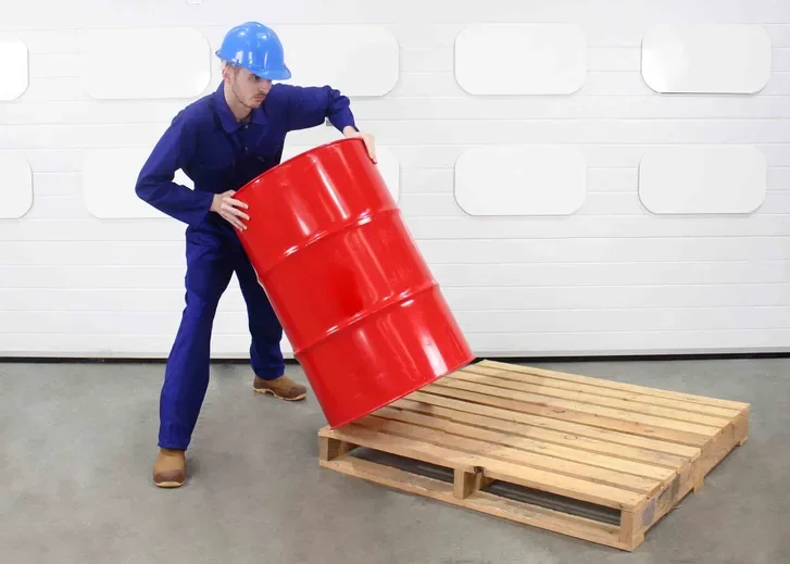 man improperly rolls a drum off a pallet