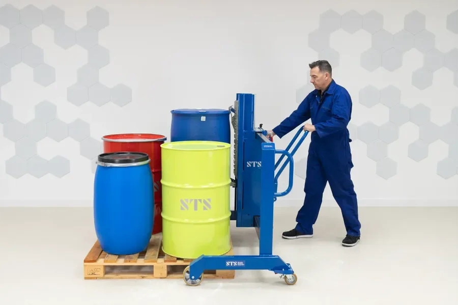 Operator is picking up a plastic barrel with a drum lifter that straddles the pallet