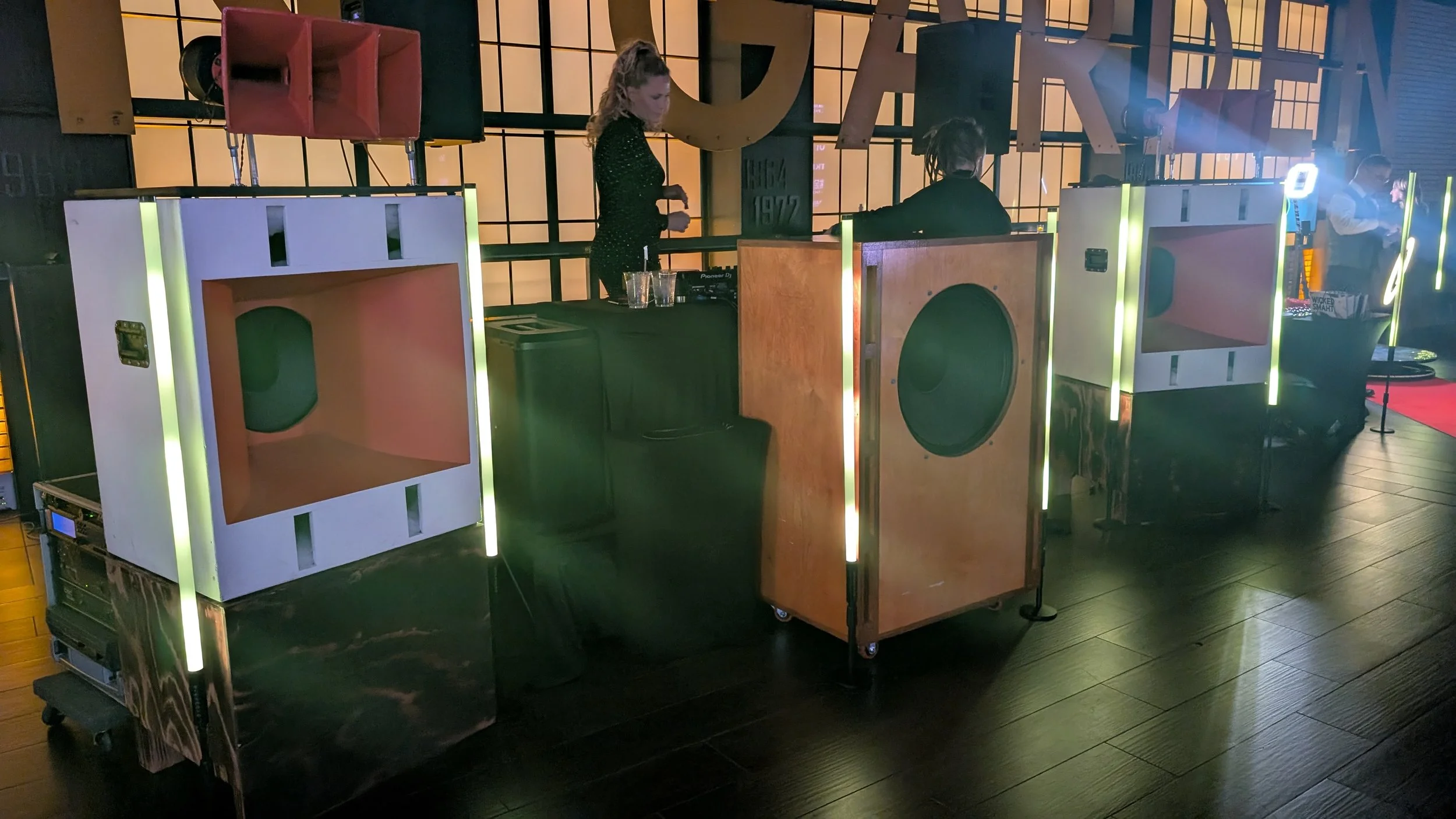 DJ booth with large speakers, decorations, and confirmation of a DJ playing music at a night event.