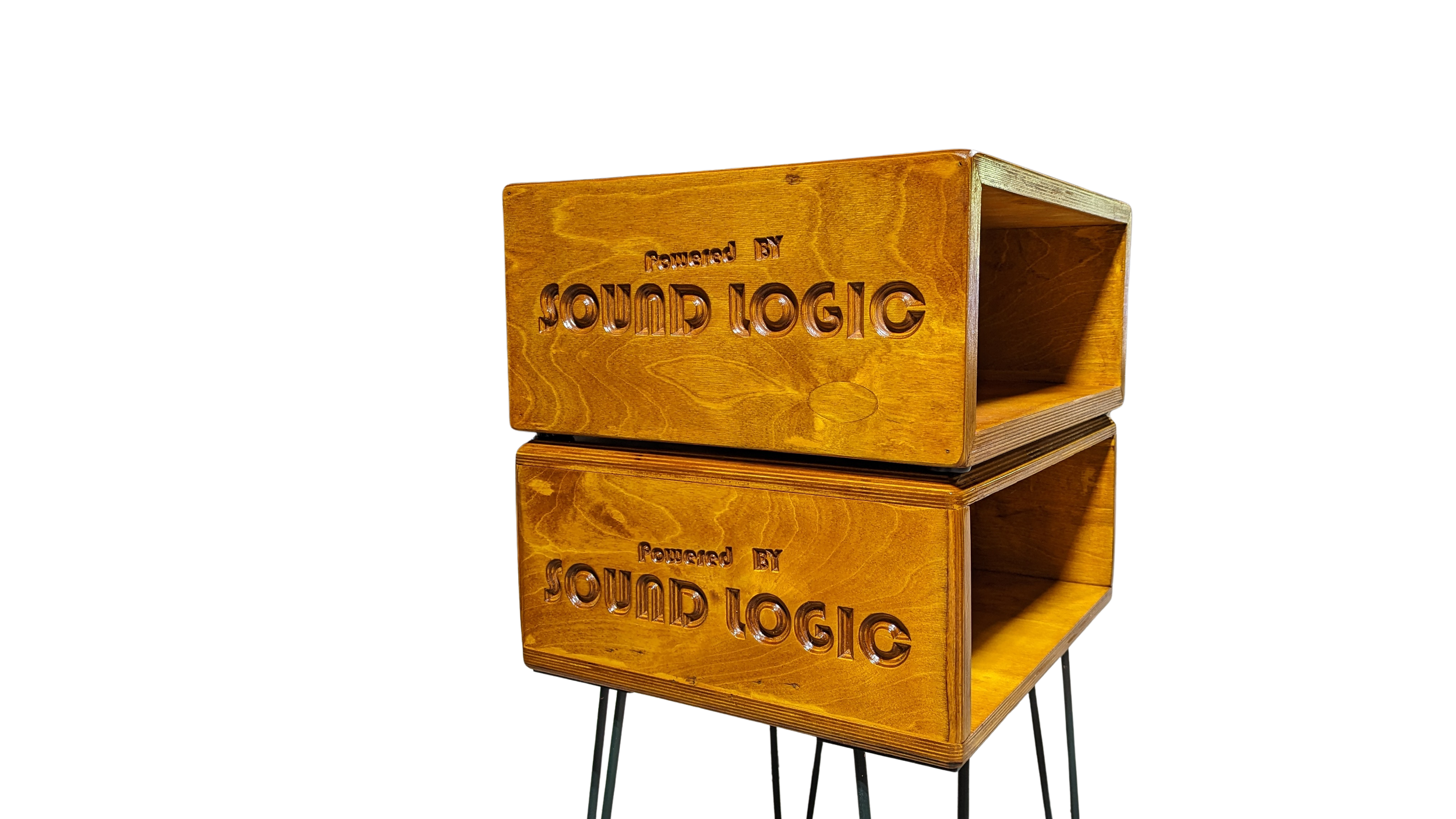 Two wooden speaker boxes with the words "Powered by SoundLogic" engraved on them, standing on black metal legs against a black background.