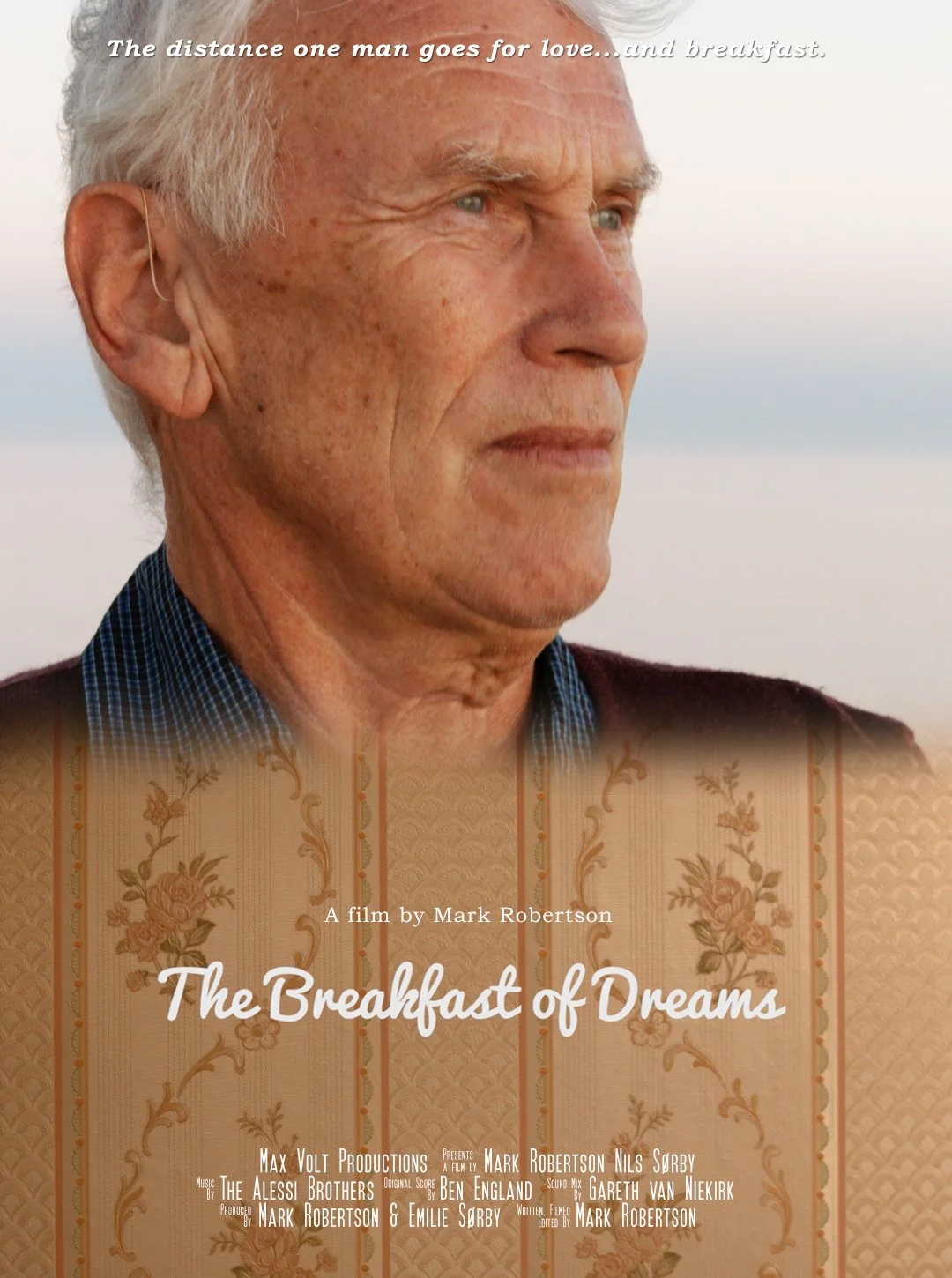 Movie poster titled 'The Breakfast of Dreams' featuring an elderly man with gray hair looking contemplative outdoors, with a background of a beach or body of water and a patterned fabric overlay at the bottom.