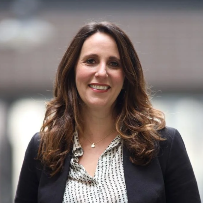 Former HJRA Executive Director Tera Hurst smiles while wearing a black blazer and a white patterned blouse, with a blurred background.