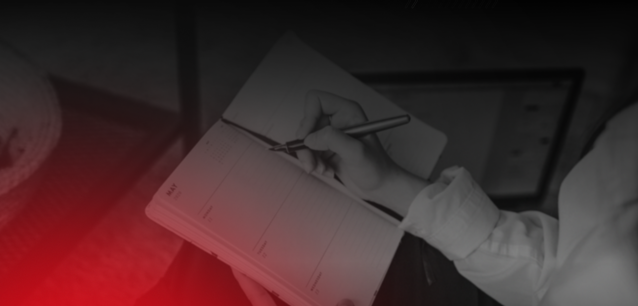 A person writing in a planner or notebook with a pen.