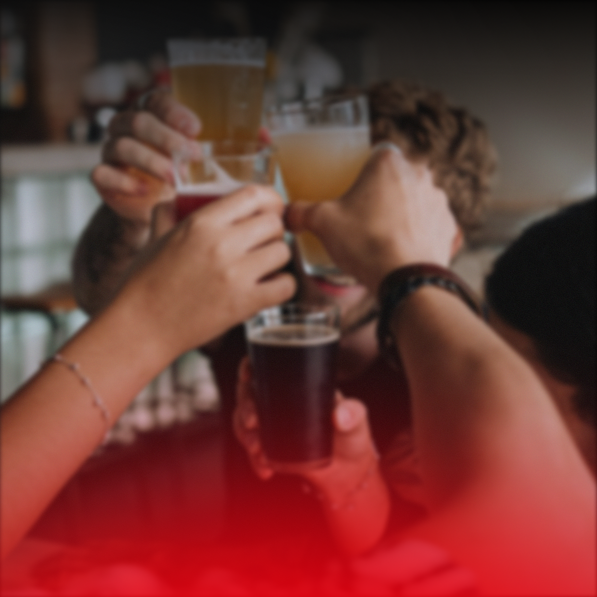 People raising colorful drinks in a toast at a bar or restaurant.