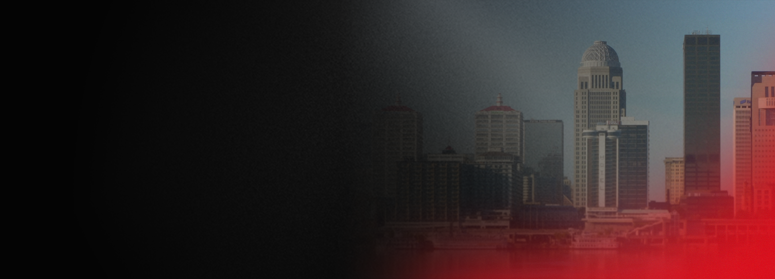 City skyline with tall skyscrapers and a domed building, partially obscured by darkness and red lighting.