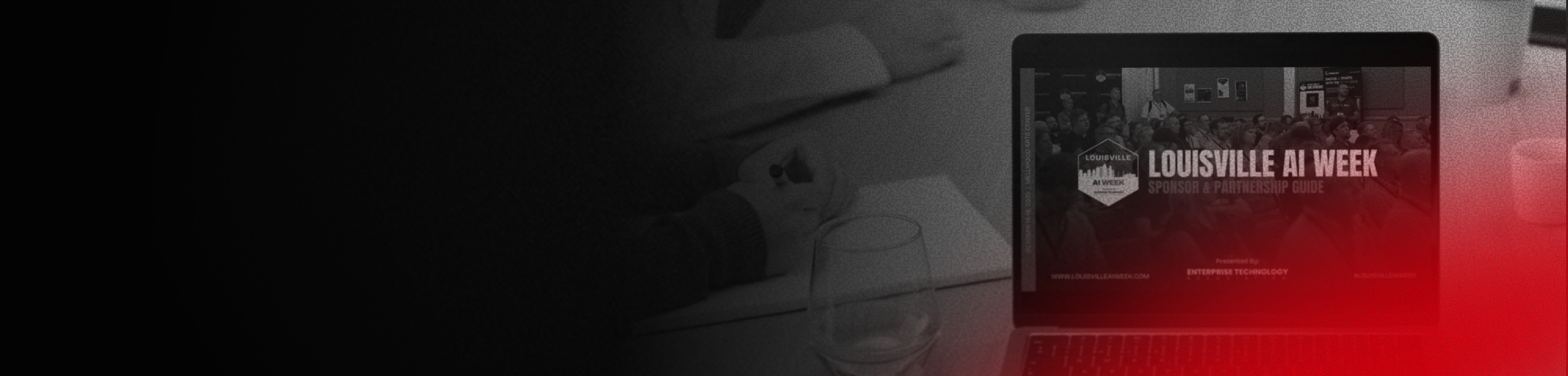 Laptop displaying an event called Louisville AI Week with a crowd in the background, a hand holding a pen, and a glass of water on a table.