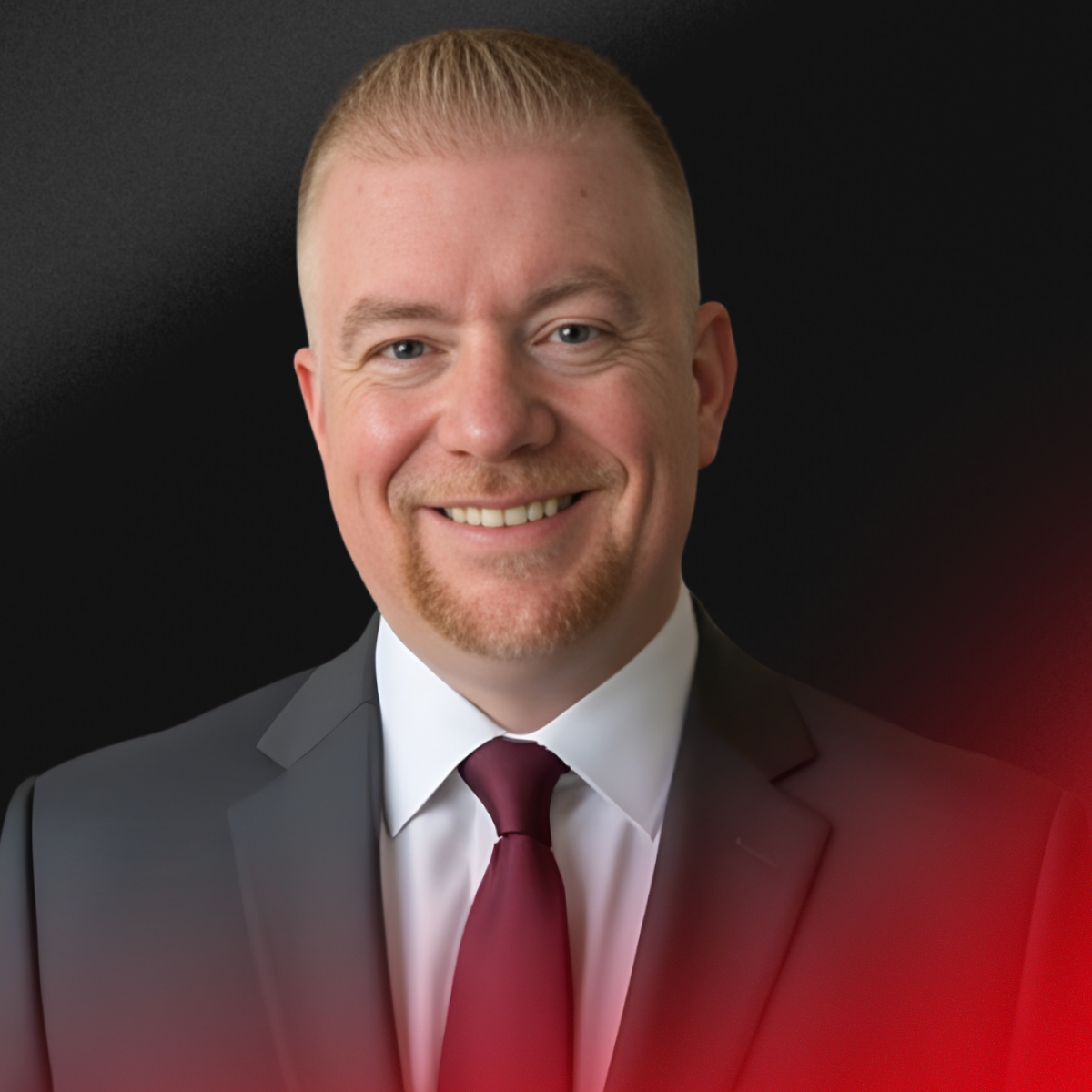 Blurred image of a person with short dark hair, wearing a black top, against a light background.