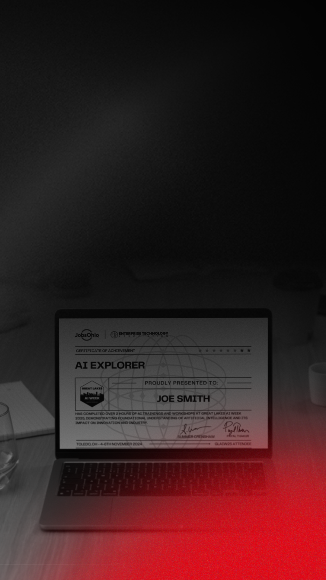 A laptop displaying a certificate of achievement titled 'AI Explorer' awarded to Joe Smith, during Great Lakes AI Week 2024, with signatures at the bottom, placed on a desk with a glass of water and a cup nearby.