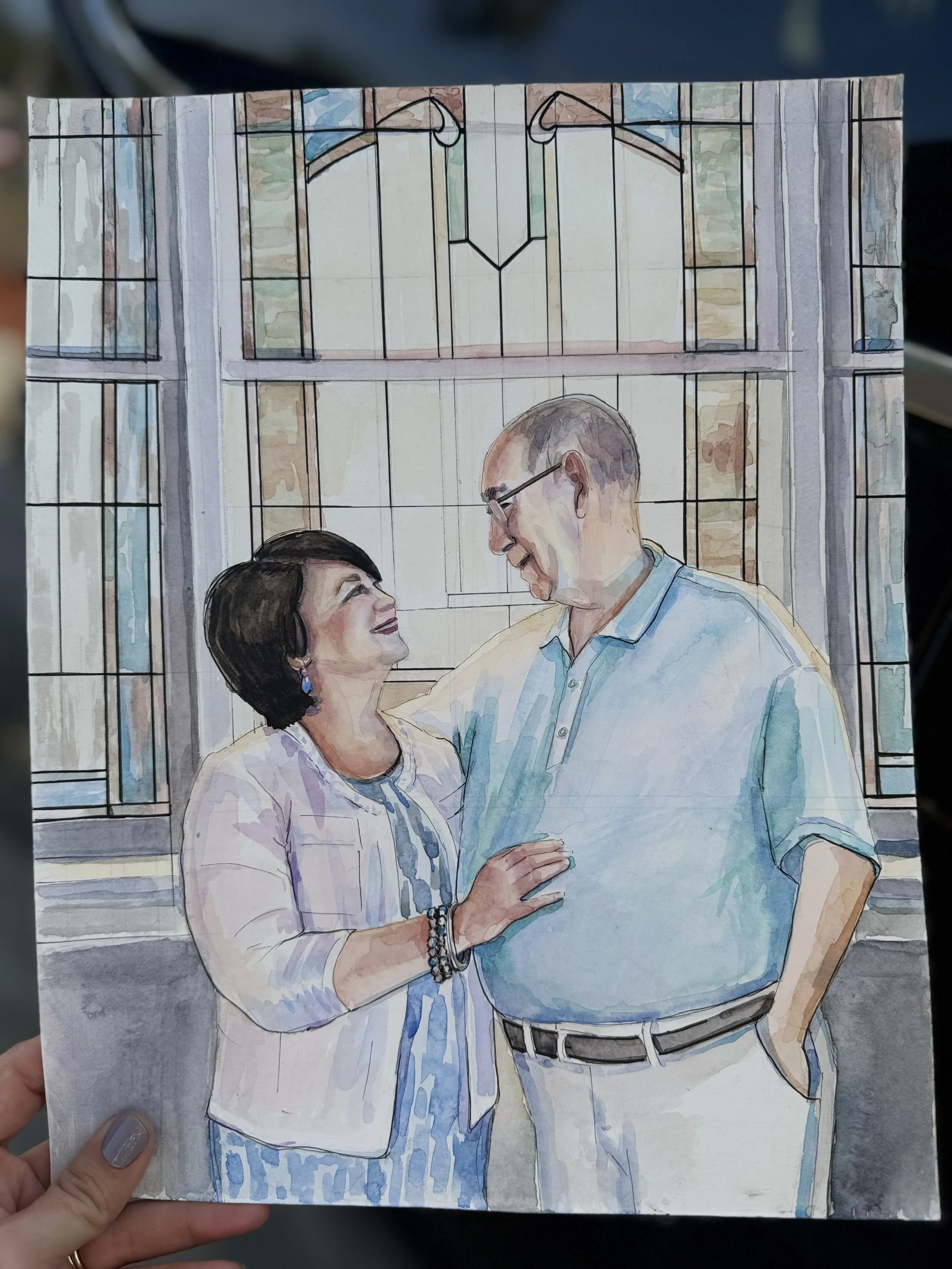 Watercolor painting of a middle-aged woman with dark hair and earrings, and a middle-aged man with glasses and light-colored shirt, smiling and looking at each other inside a building with large windows.