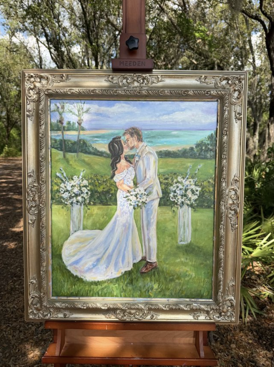 Painting of a bride and groom kissing outdoors. The bride has dark hair and wears a white wedding dress, holding a bouquet of flowers. The groom has light-colored hair, glasses, and wears a light suit. They stand on green grass with a backdrop of tre