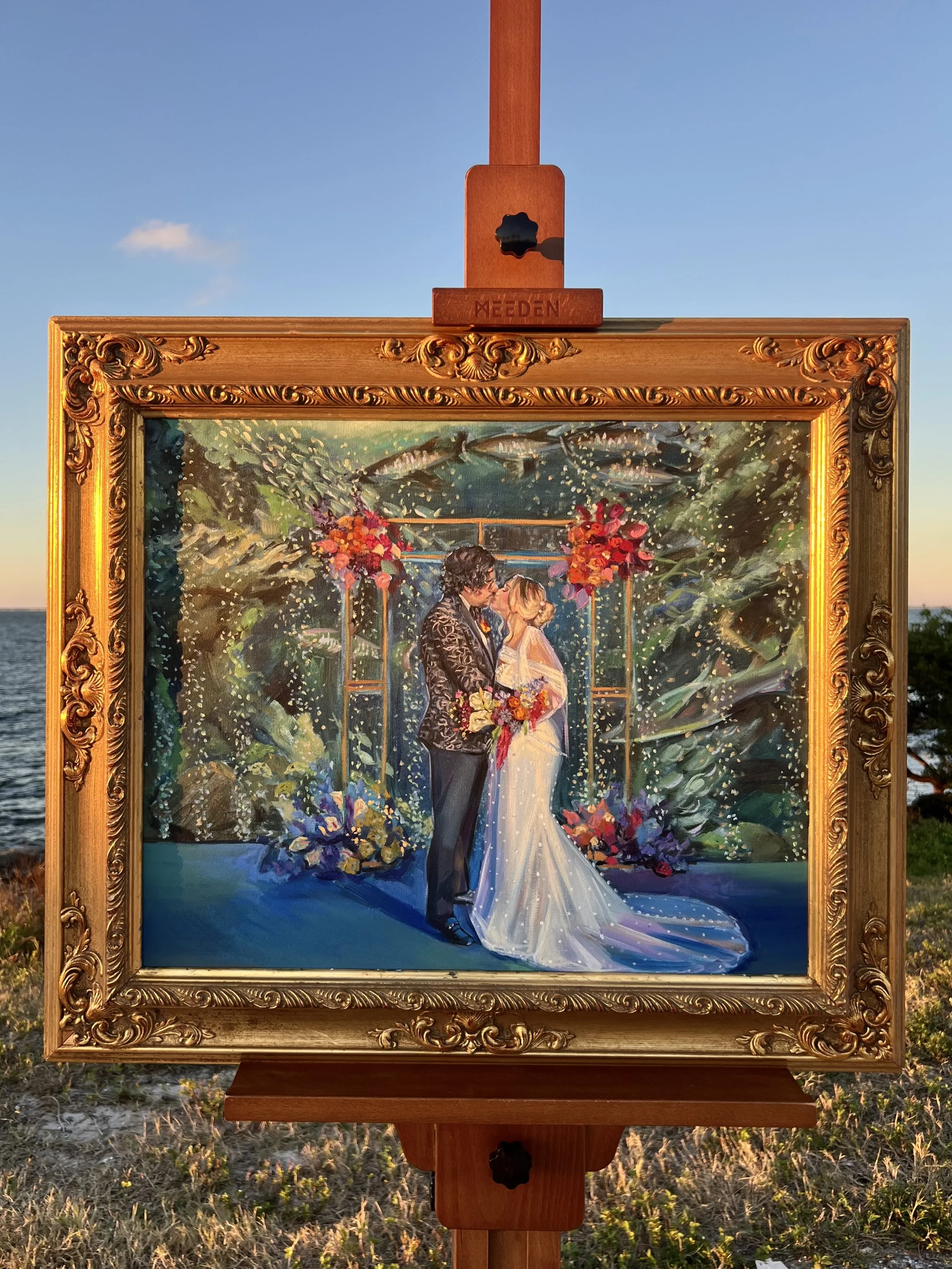 Framed painting of a bride and groom standing in front of a wedding arch with pink and red flowers, and an aquarium filled with fish and bubbles.