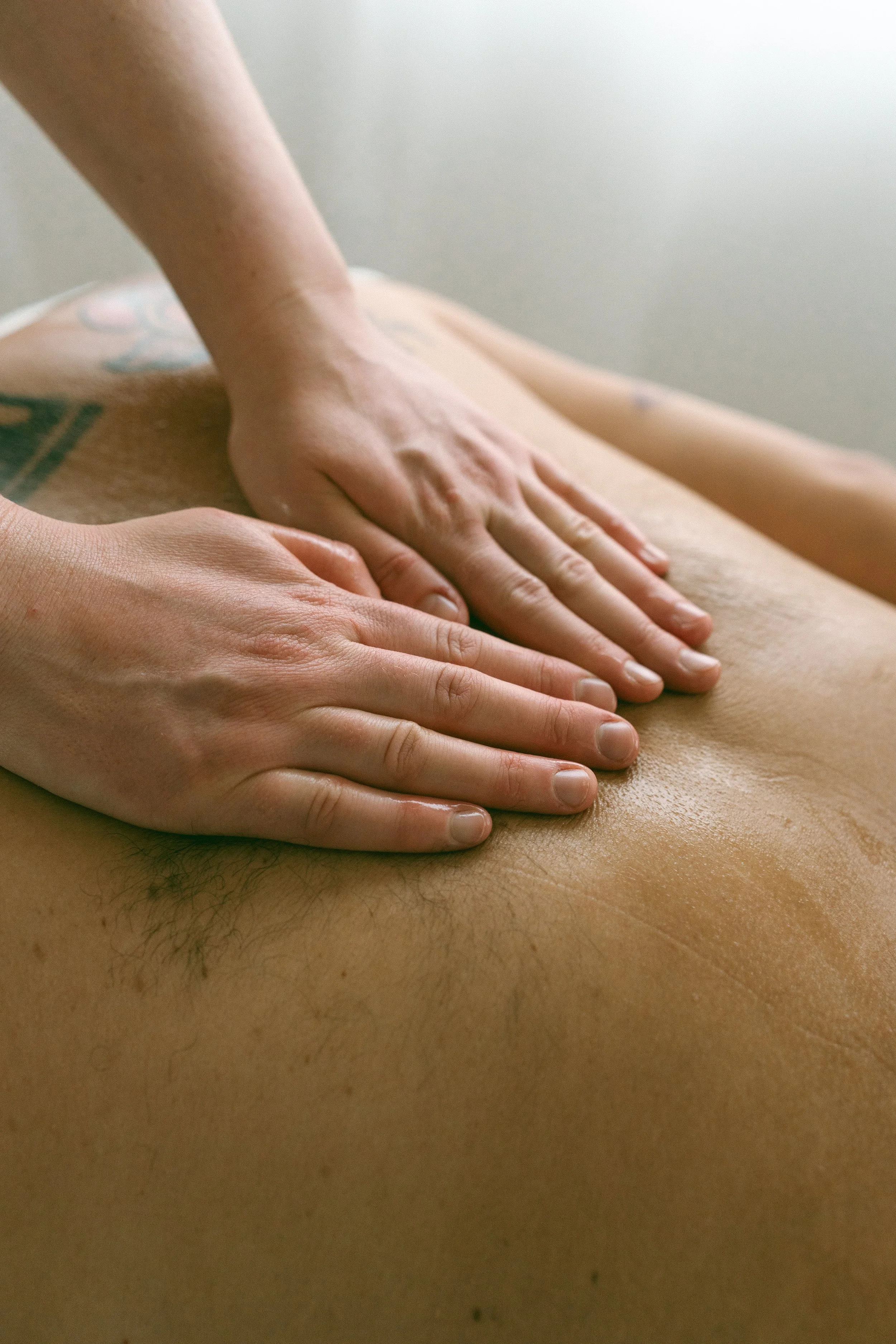 A person receiving a massage with hands pressing on their bare back.