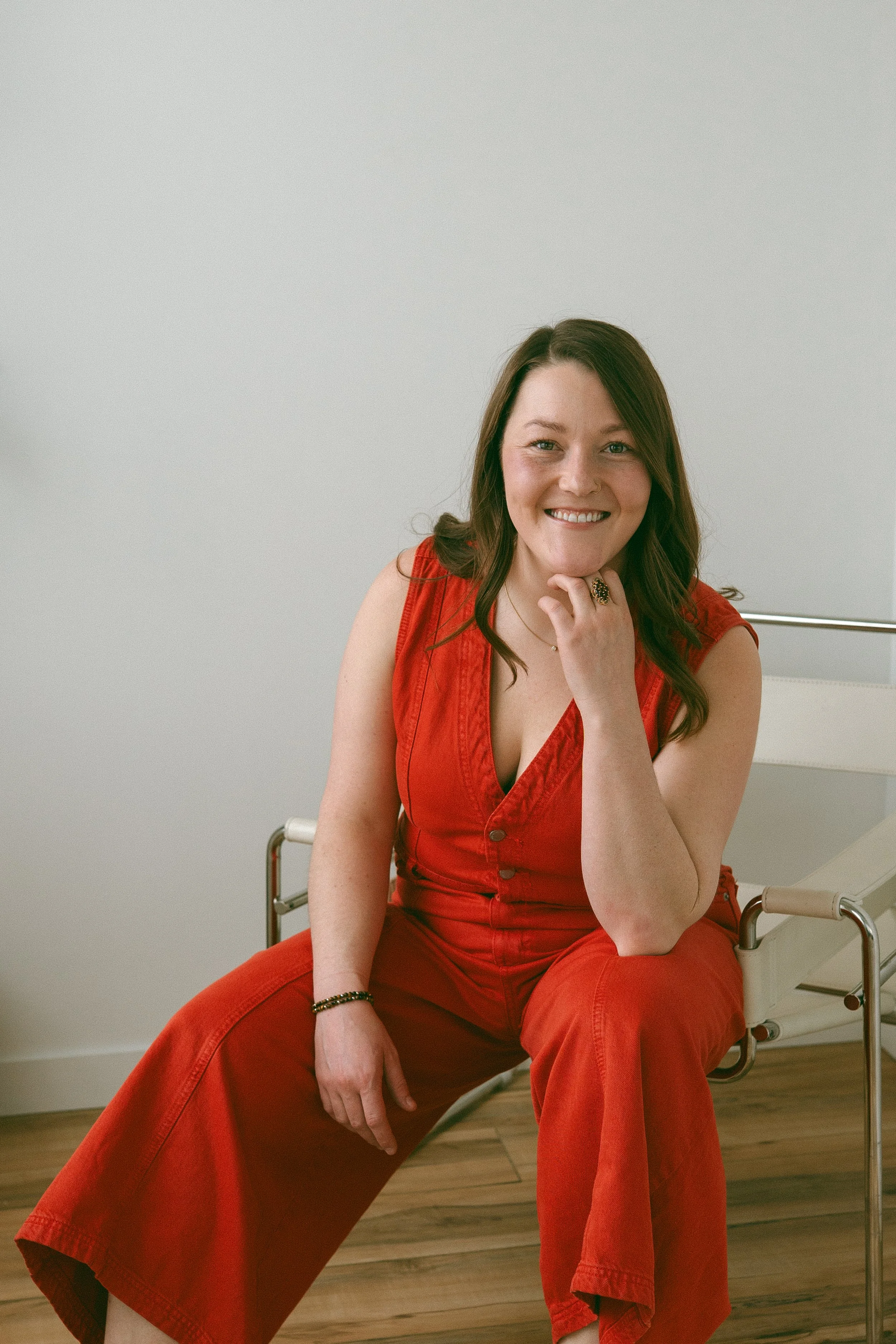 Emma Johannesson - Registered Massage Therapist, smiling warmly wearing a red jumpsuit