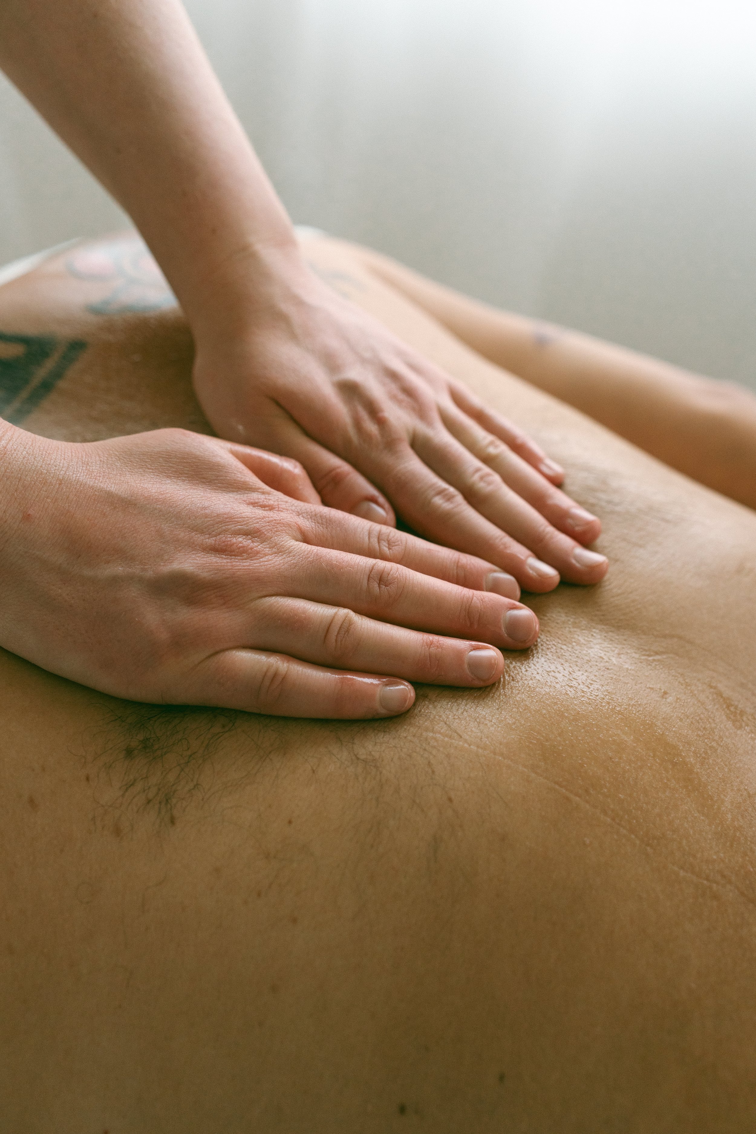 Close-up of a person giving a massage on a person's back with their hands, in a soothing setting.