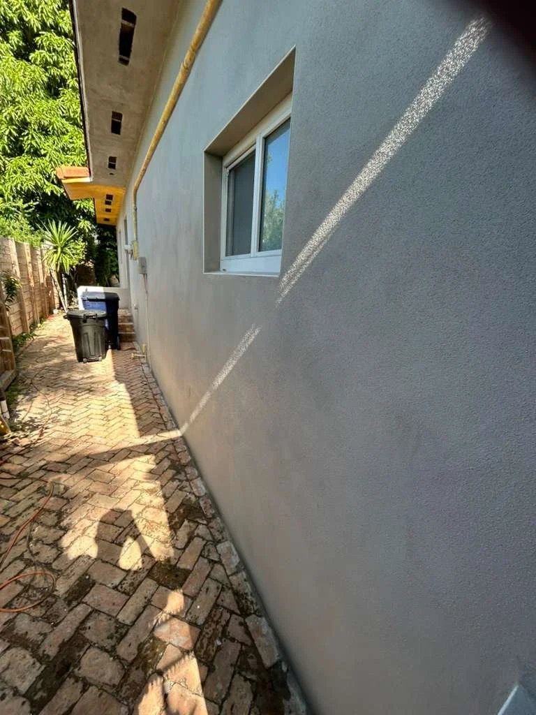 Construction workers renovating a building's exterior wall with scaffolding and painting supplies.