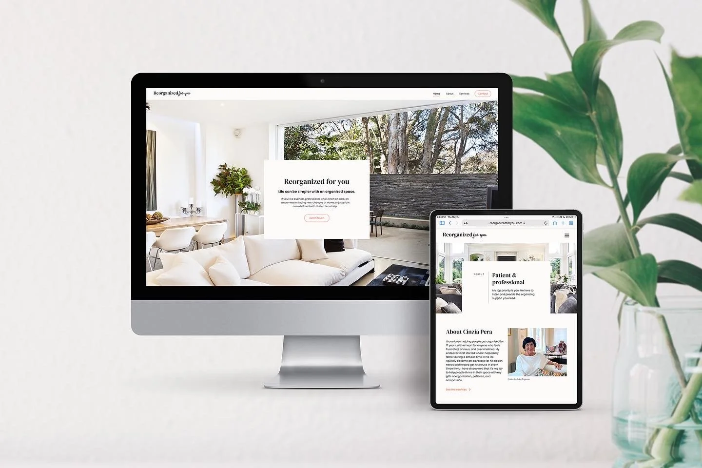 A desktop computer and a tablet displaying website pages, with a background of a bright living room and a plant on the right side.