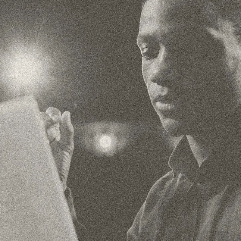 Black and white photo of a man looking at a smartphone, with a focused expression.