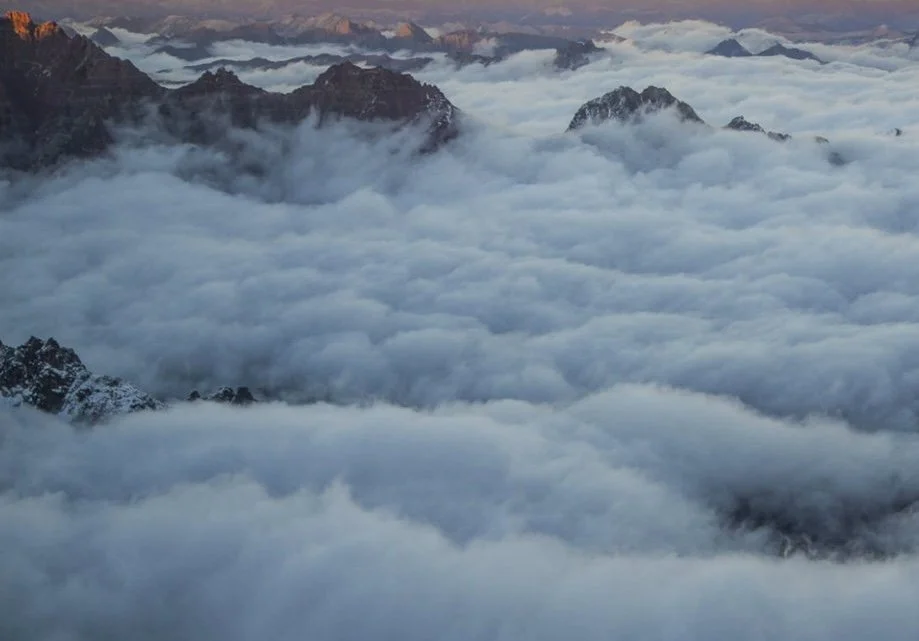 Cloud-covered mountains at sunrise or sunset with misty sky