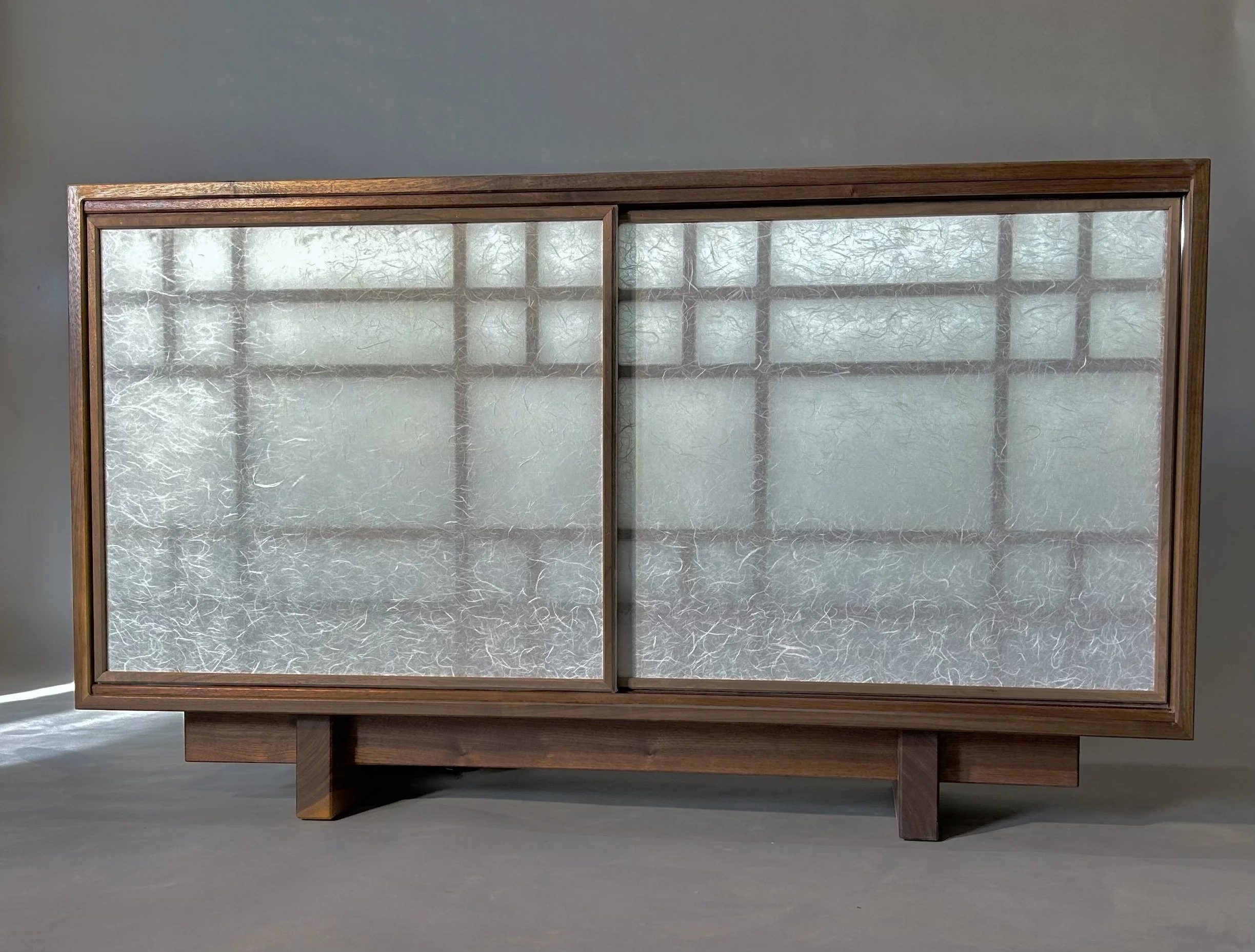 Mid-century modern wooden cabinet with sliding glass doors and textured glass panels.