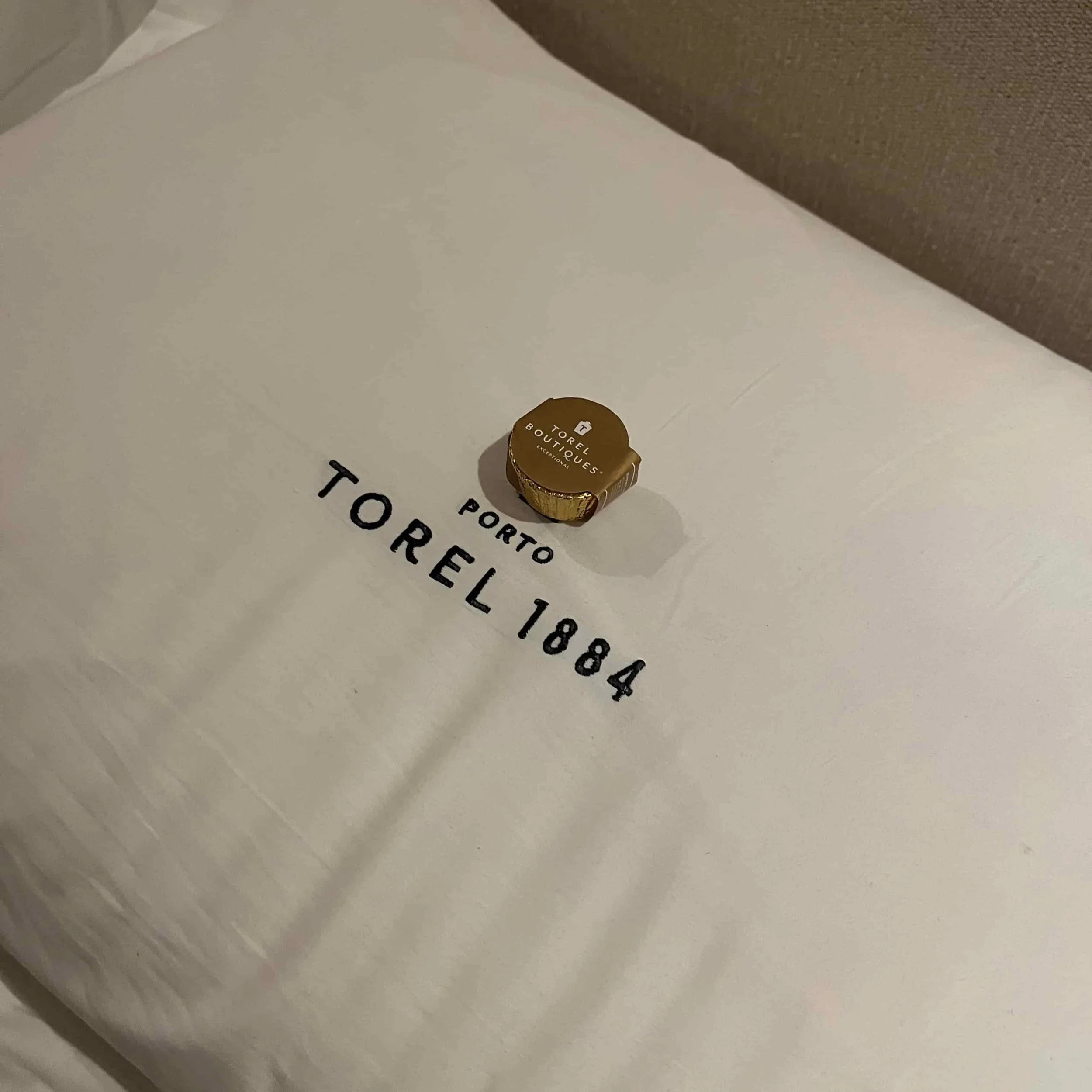 A hotel pillow with a chocolate on it.