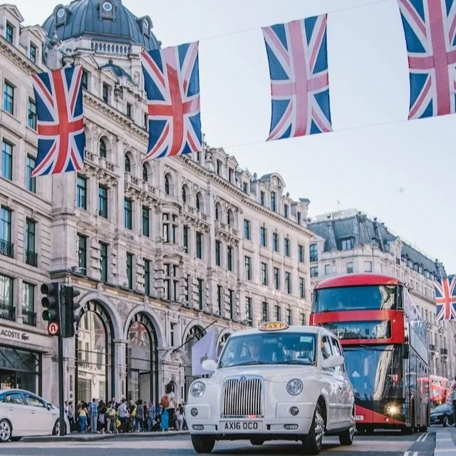 A double decker bus drives under a row of Union Jacks in London.