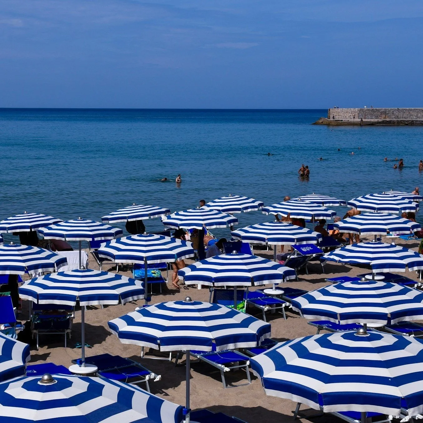 Umbrellas dot the sand at a beach club in Cefalu, Italy.