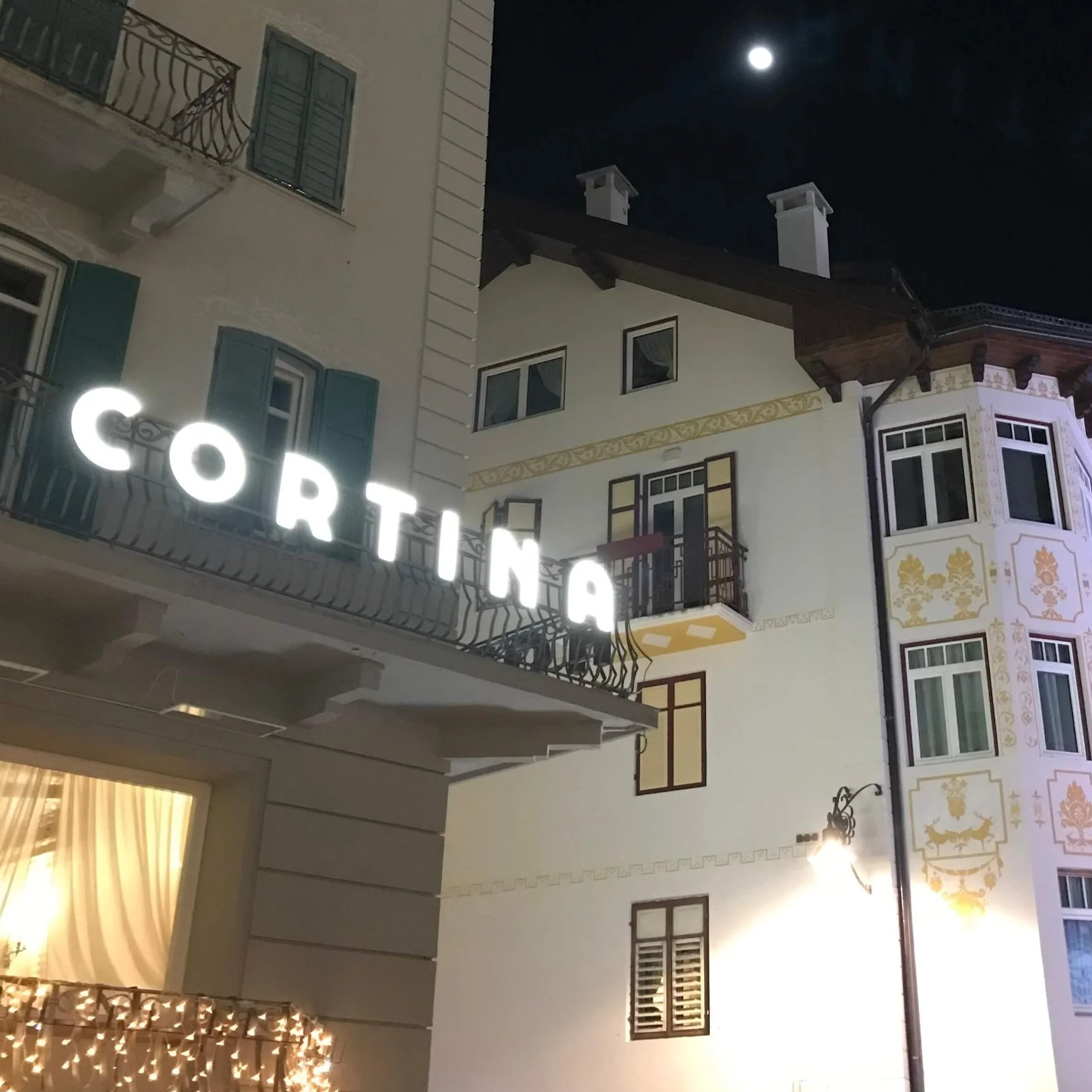 An illuminated Cortina sign at night.