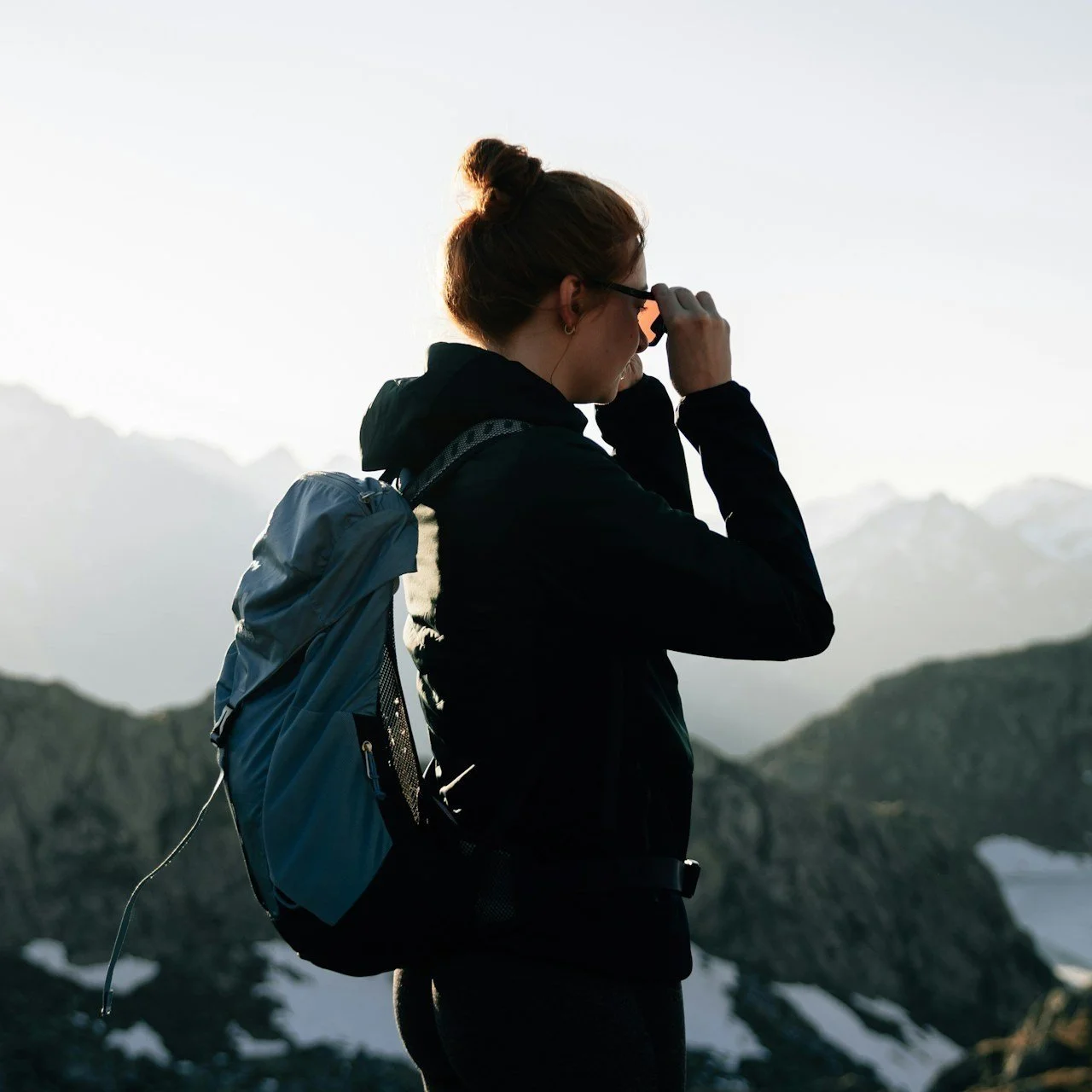 A woman wearing a medium backpack while hiking in the mountains.