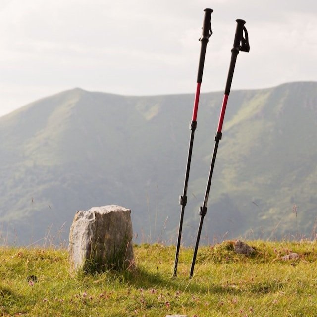 A pair of hiking poles stuck in the earth at the edge of a mountain.