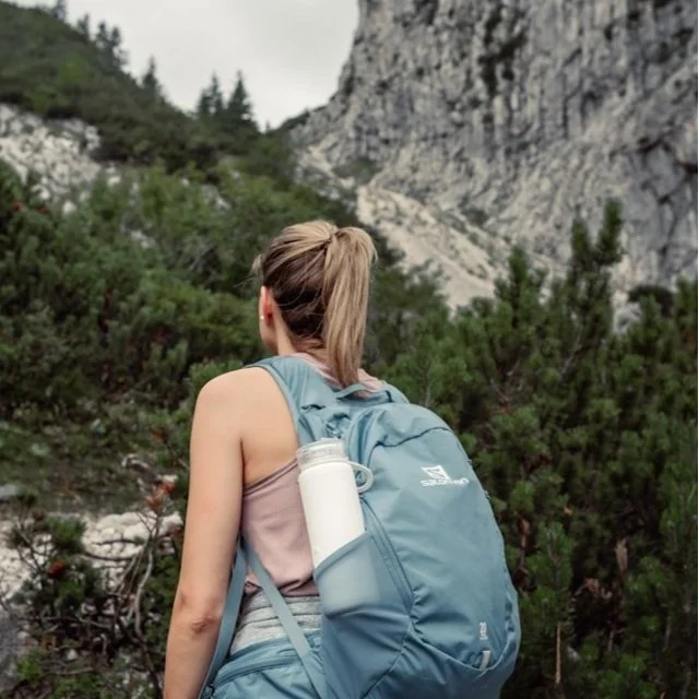 A woman wearing a backpack with water bottle while hiking.