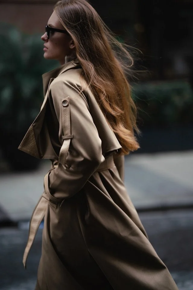 A woman wears a trench coat.