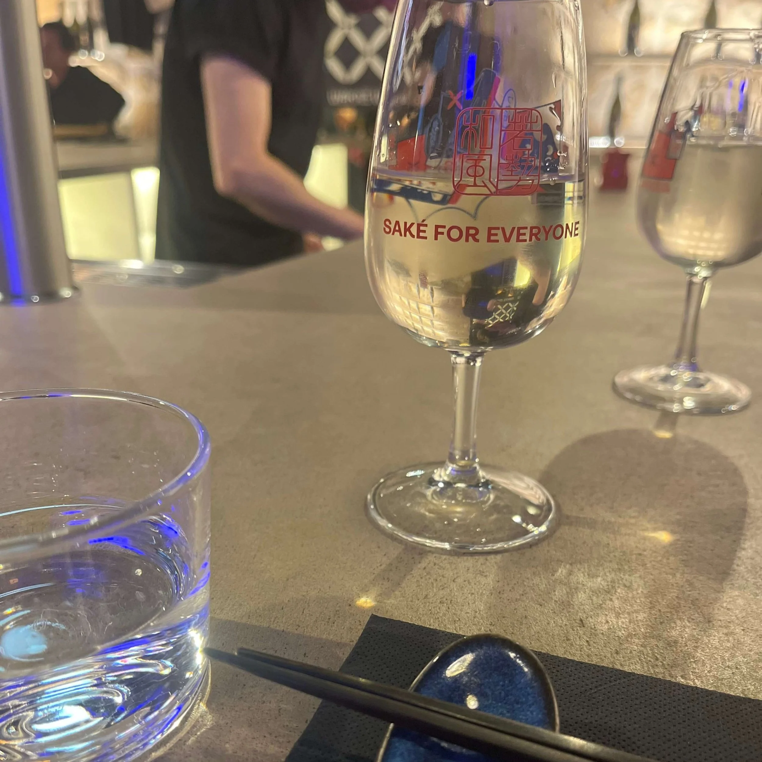 A glass reading "SAKE FOR EVERYONE" at Parisian Sake Brewery WAKAZE.