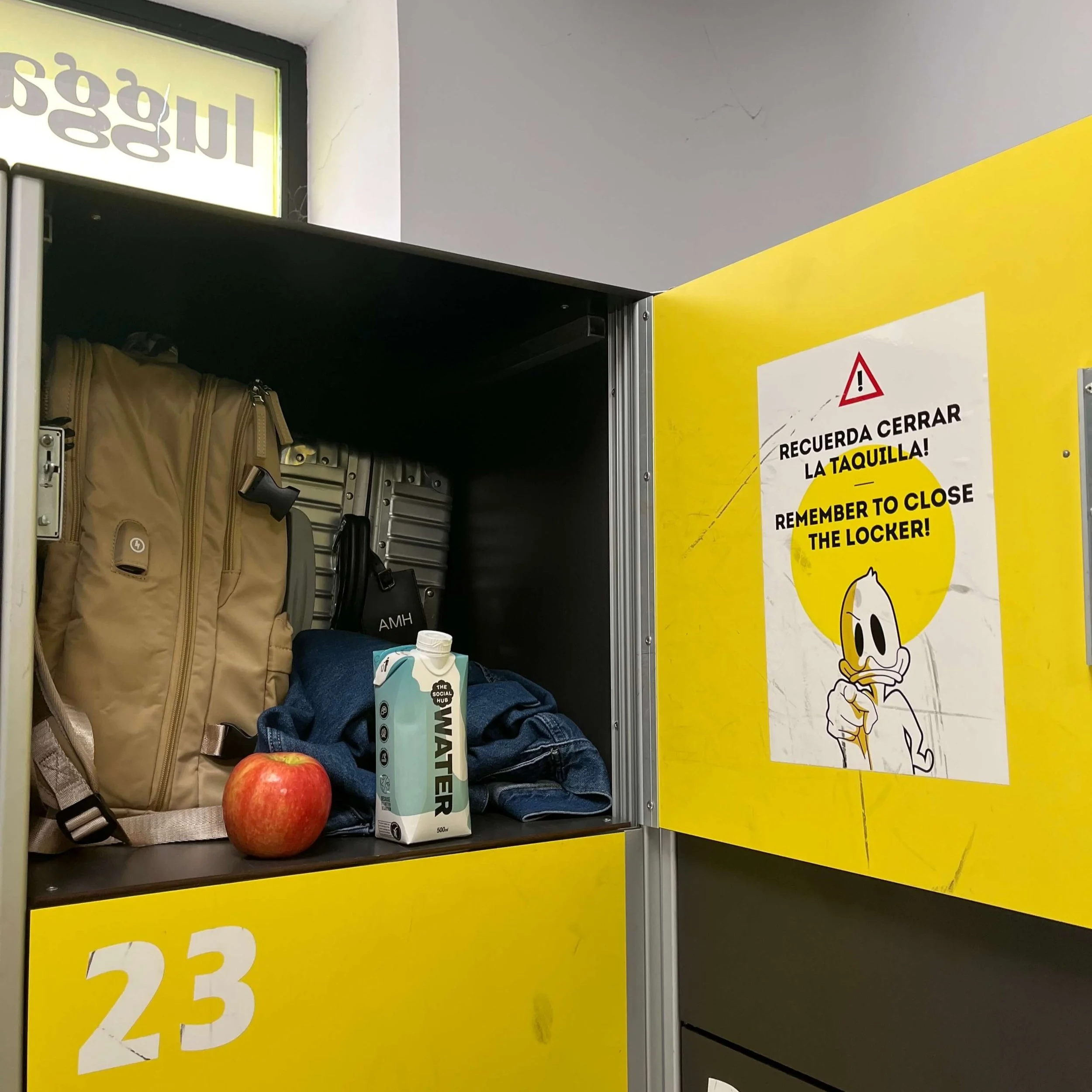 A close up of an open luggage locker showing how a backpack and carry on can fit inside.