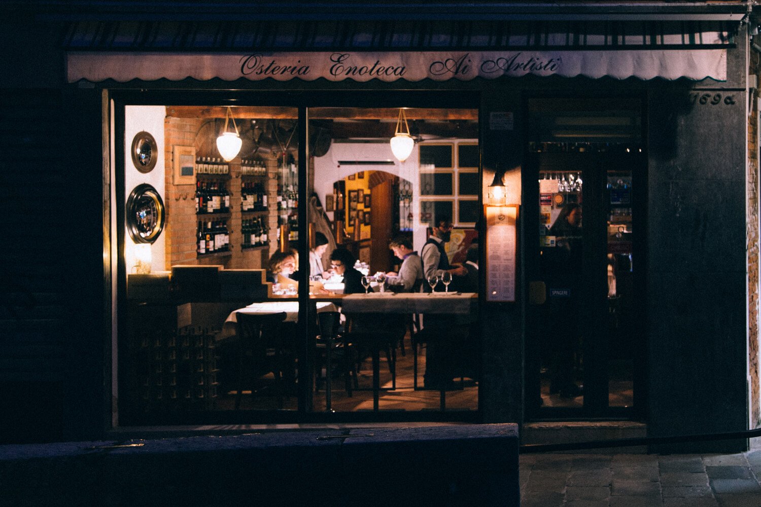 The exterior of Osteria Enoteca Ai Artisti in Venice after dusk.