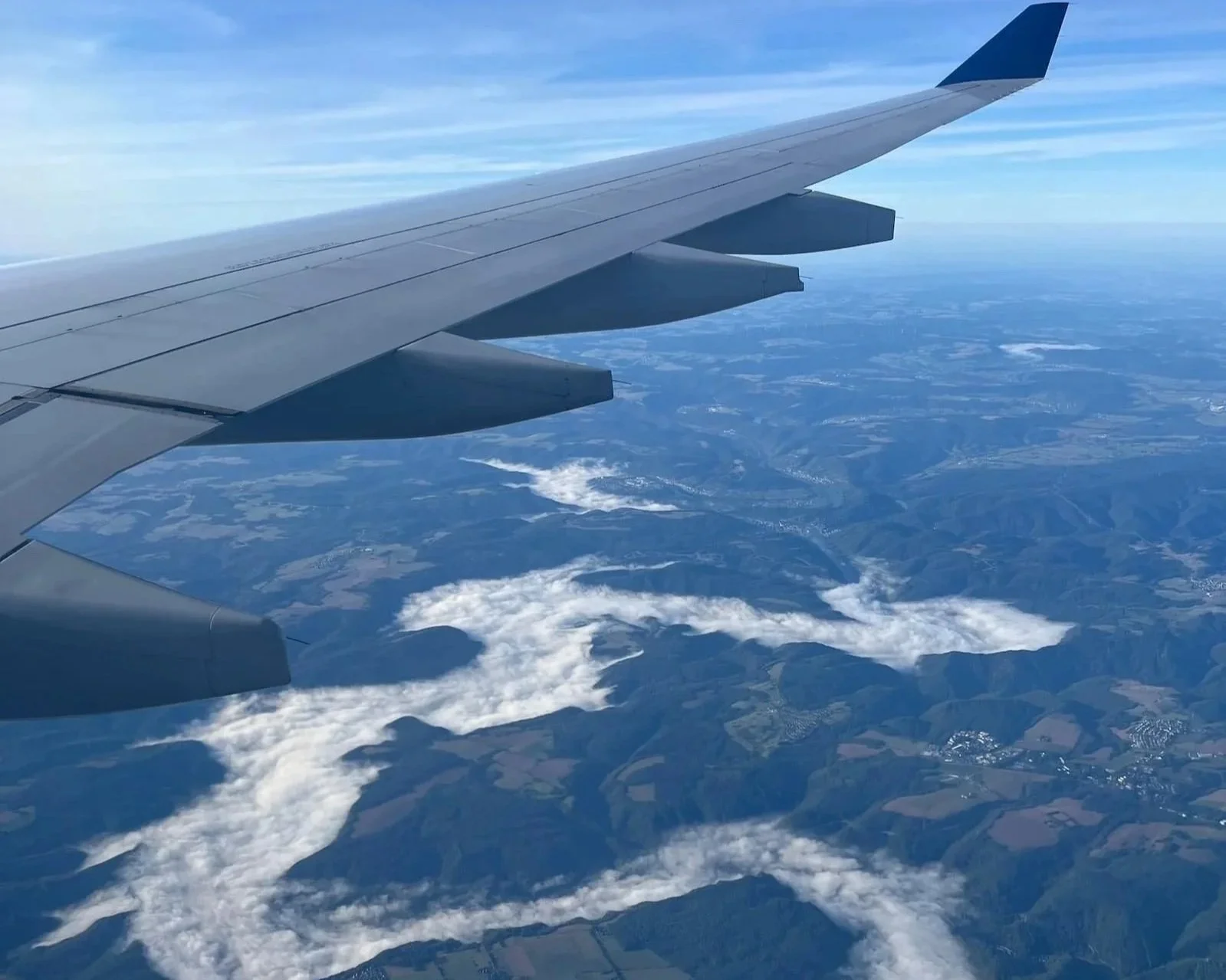 The wing of a plane above a valley filled with fog in Germany.