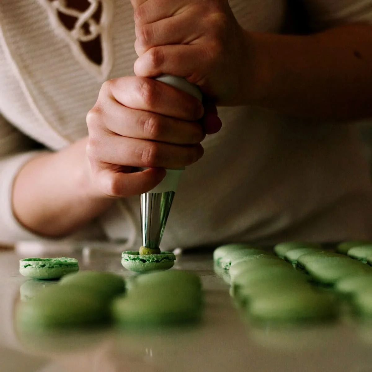A pair of hands filling macarons.