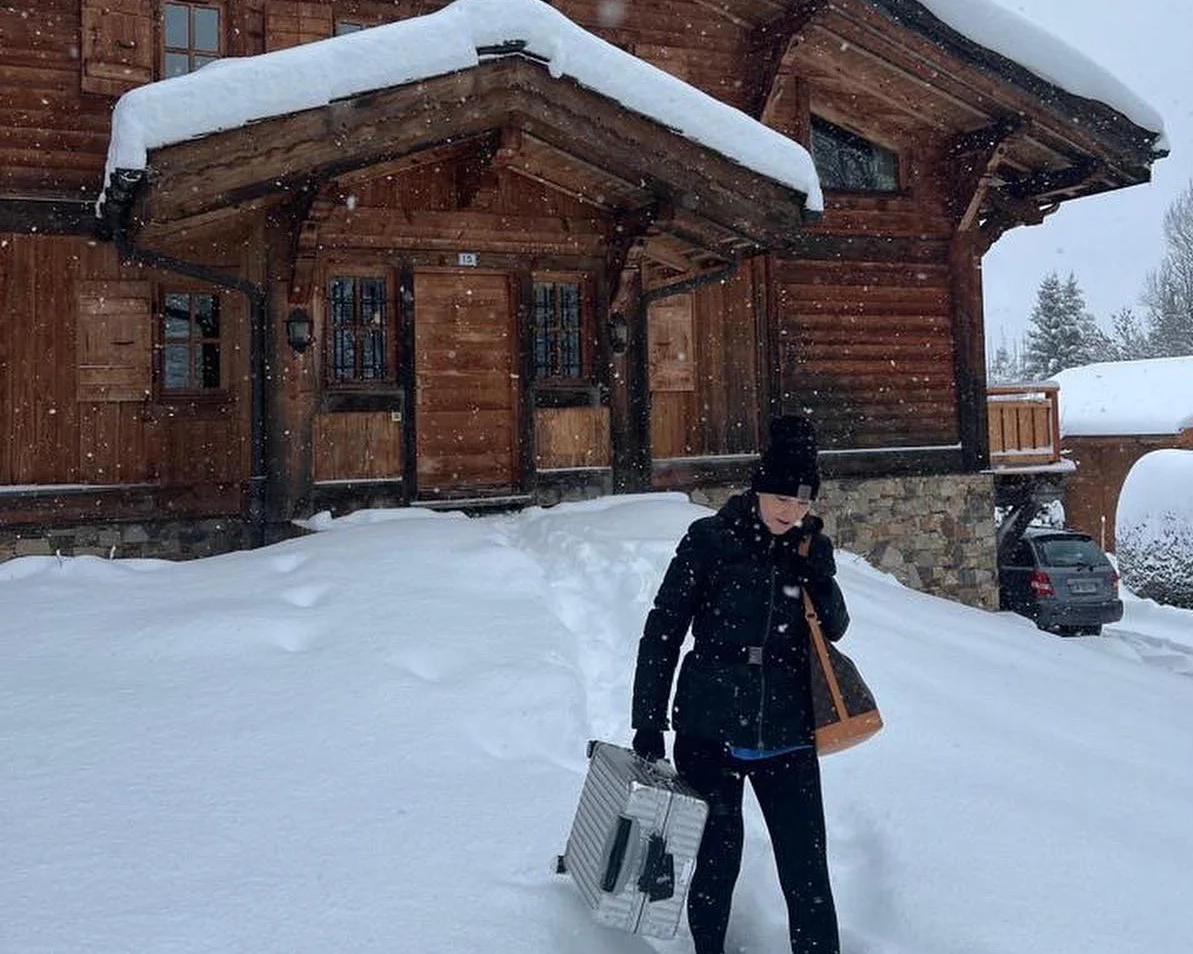 The author carrying a suitcase through the snow near a winter ski chalet.