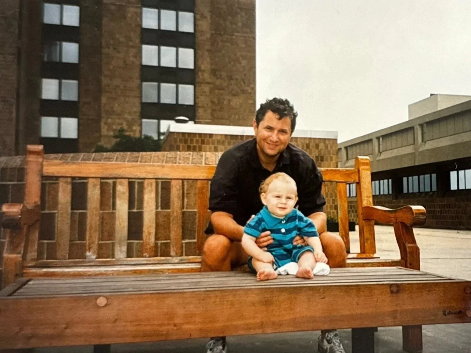 Baby Josh Arnon sitting on a bench with his father at Waterside Plaza.