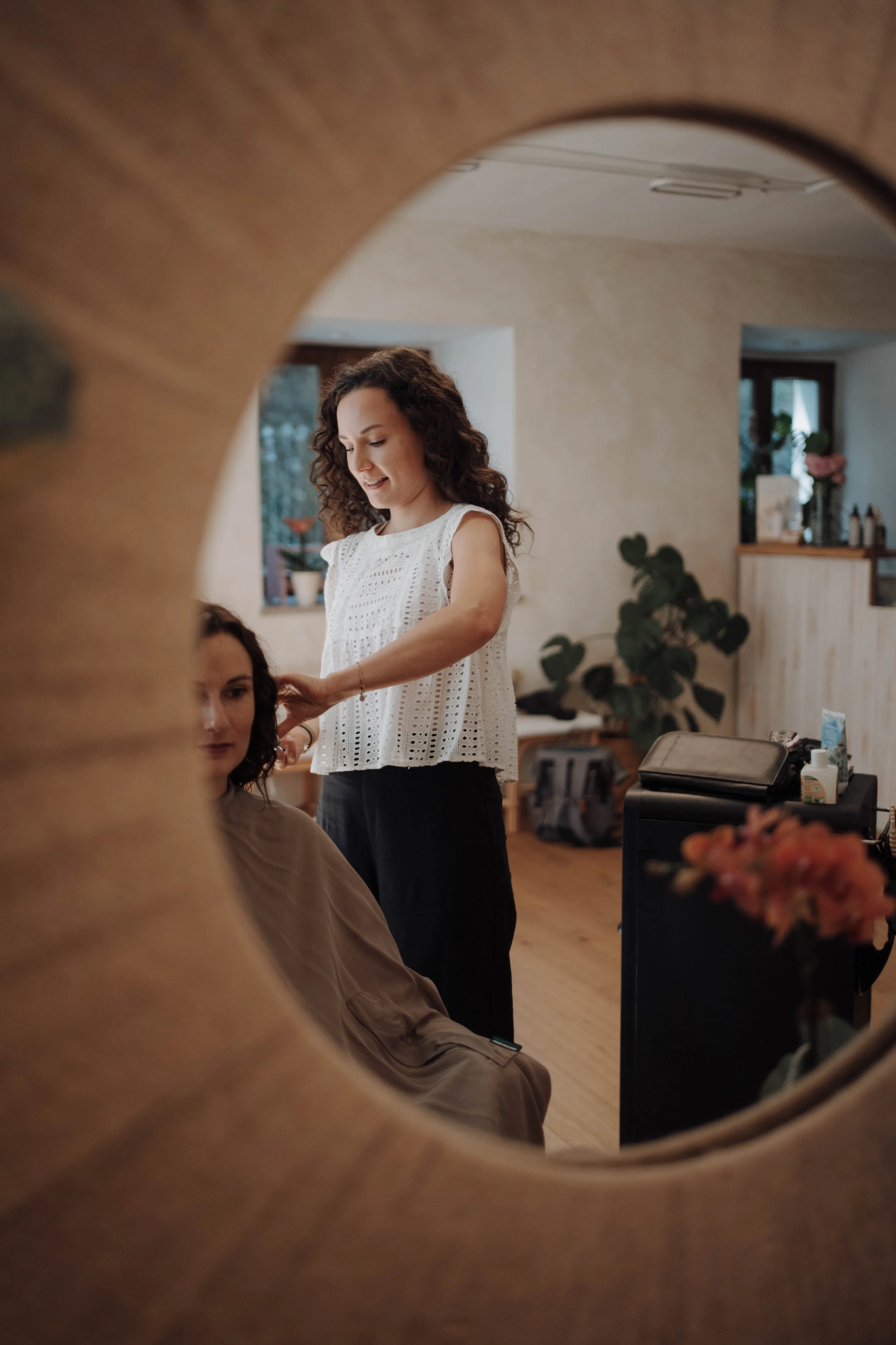 Friseurin macht eine Frisur bei einer Kundin in einem gemütlichen, gut beleuchteten Salon.