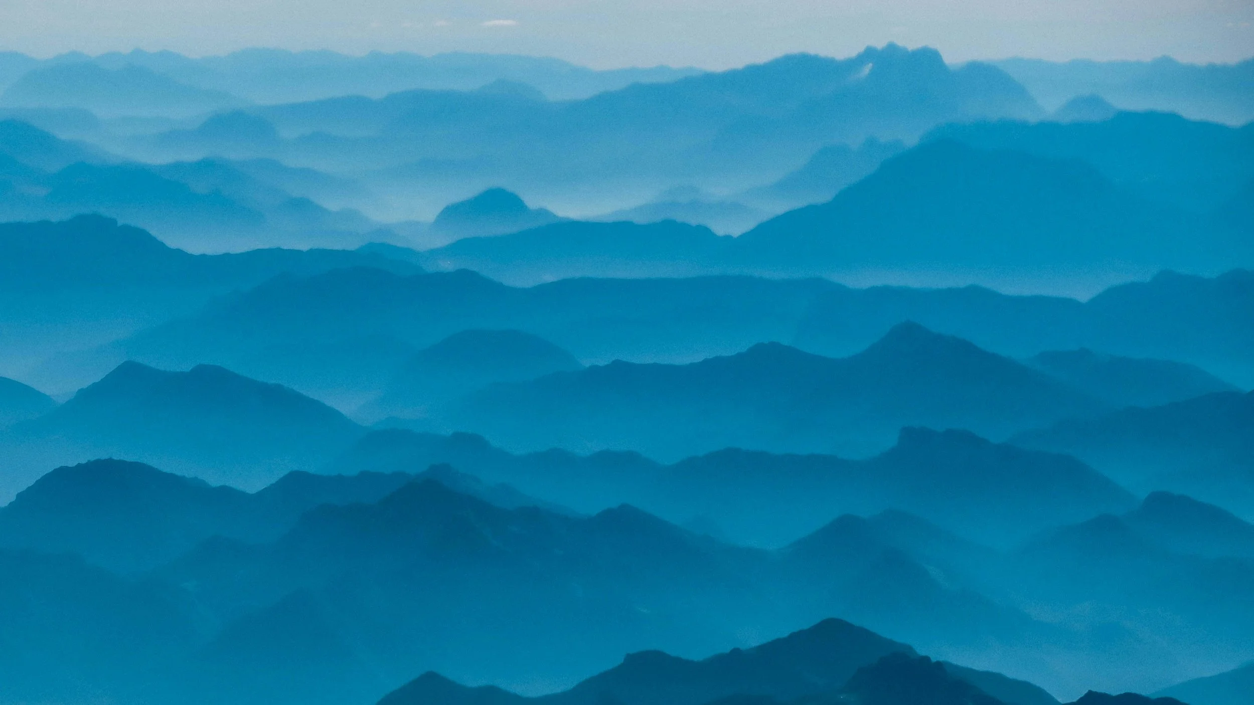 Multiple layers of blue mountain ridges fading into the distance, creating a misty, layered landscape.