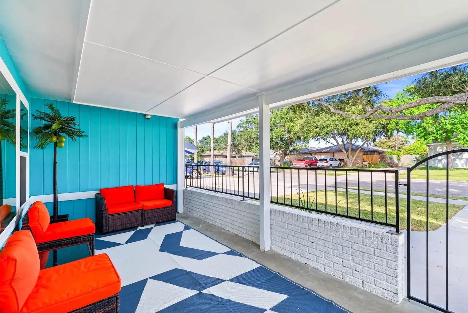 Covered front porch with red chairs and checkered rug at The Oasis Corpus Christi