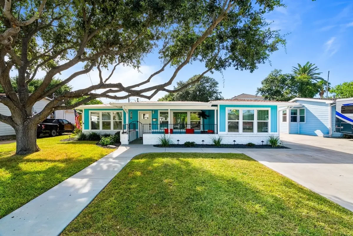 Teal exterior of The Oasis vacation rental with mature oak tree in Corpus Christi, TX