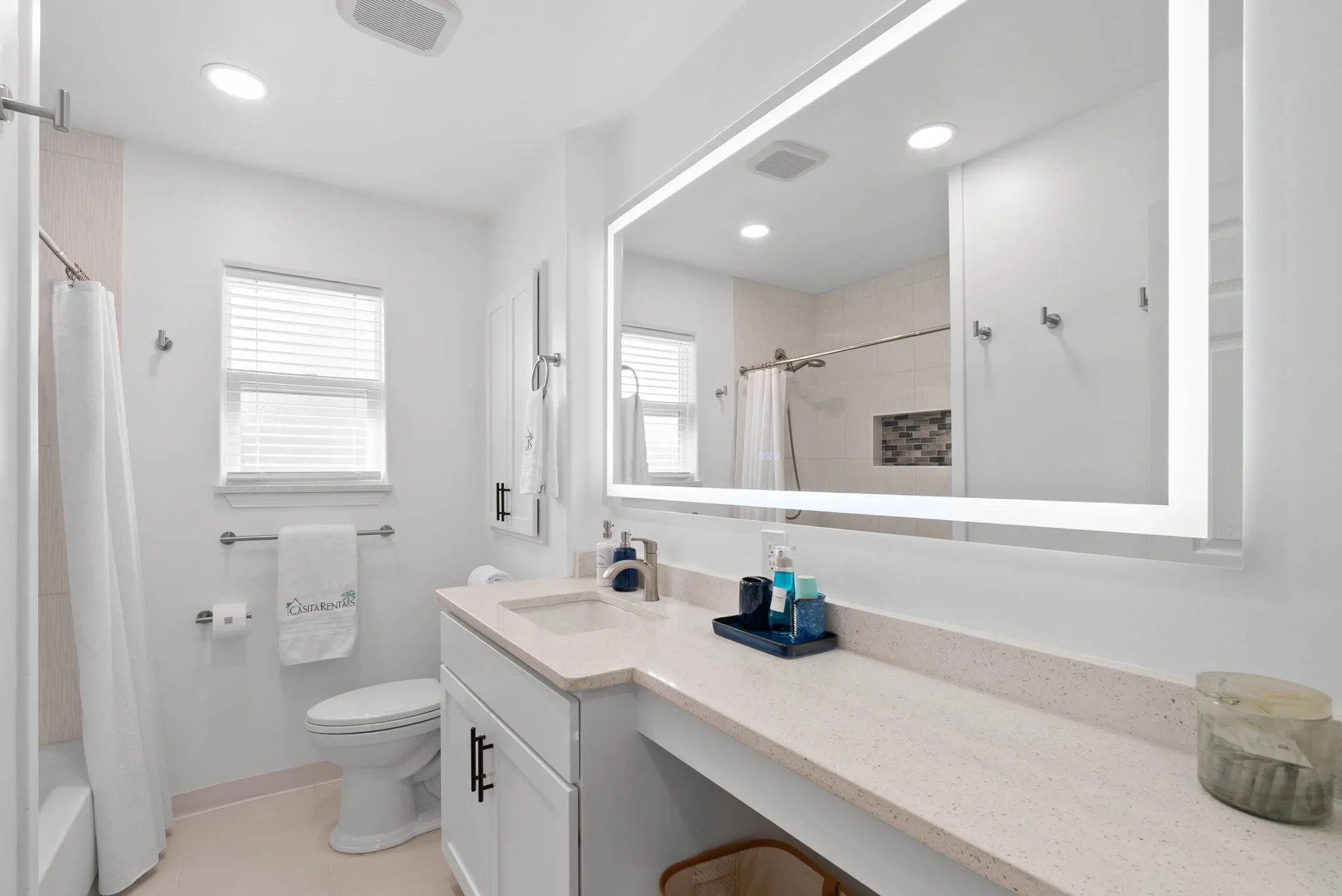 Primary bathroom with tub-shower combo and a lit vanity mirror at The Oasis