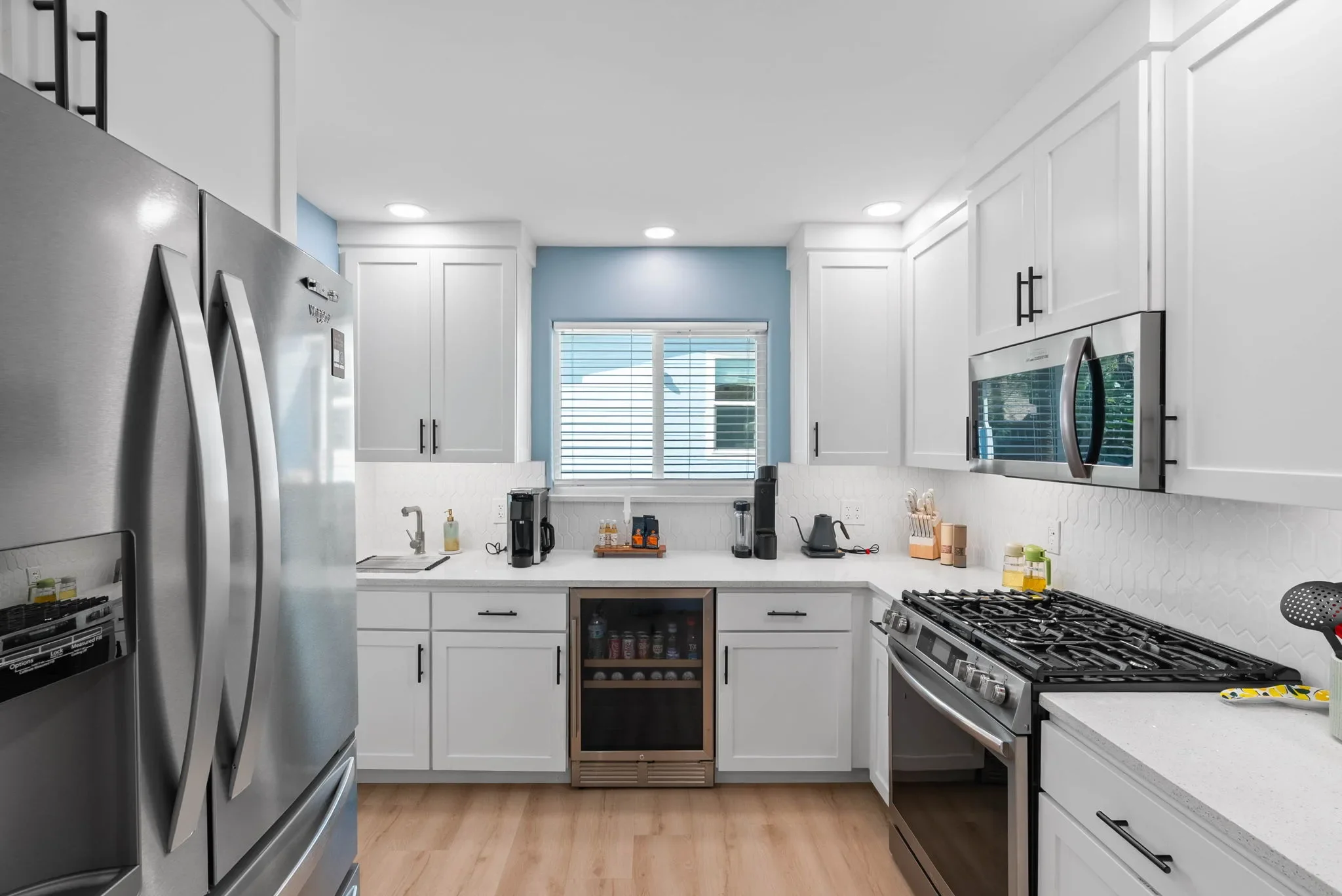 Kitchen with stainless fridge, wine cooler, and gas range at this vacation rental