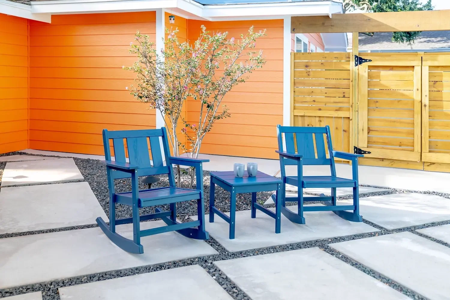 Patio seating with blue rocking chairs against an orange wall in Corpus Christi
