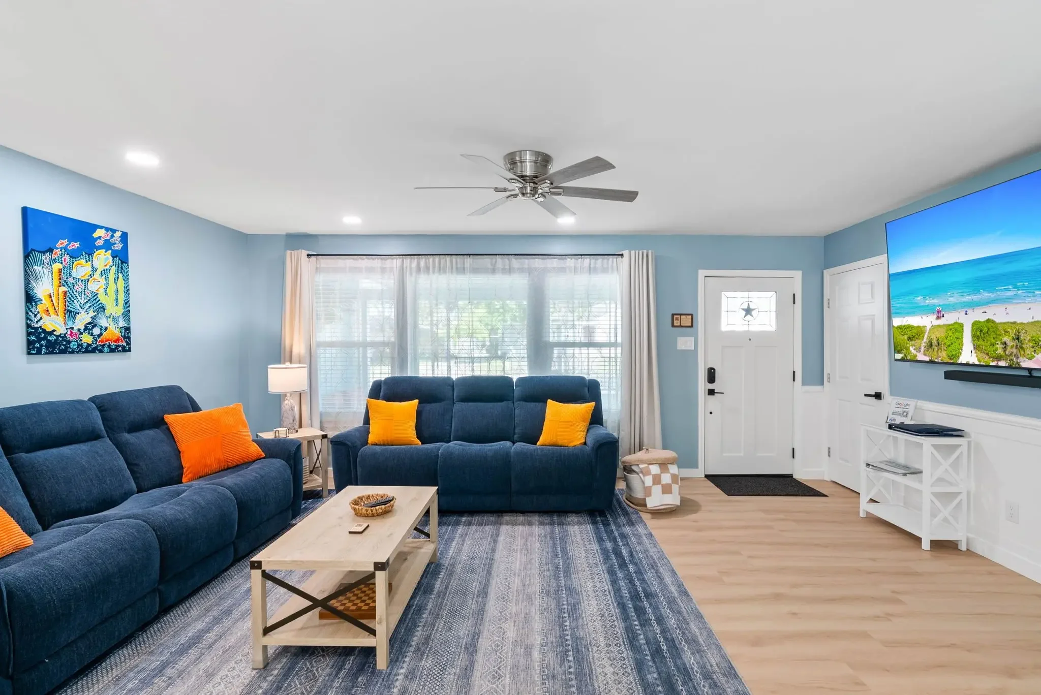 Living room with navy sofa and coastal wall art at The Oasis in Corpus Christi