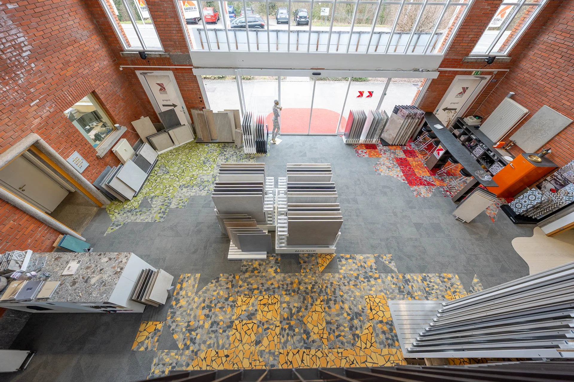 Innenansicht eines Fliesengeschäfts mit Fliesenmustern, Mustertafeln, Verkaufstresen und Sitzbereich.