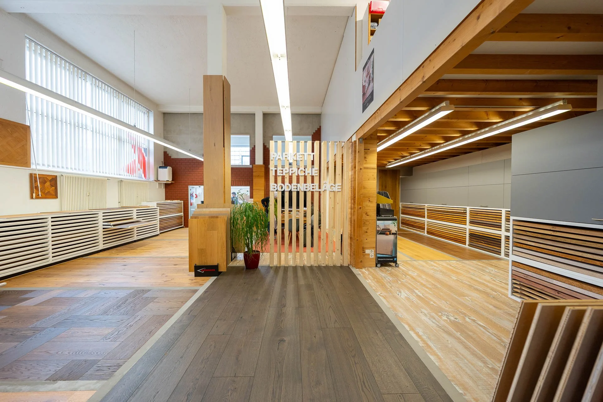 Innenraum eines Holzfachgeschäfts mit verschiedenen Holzfußböden, Schildern und Pflanzen.