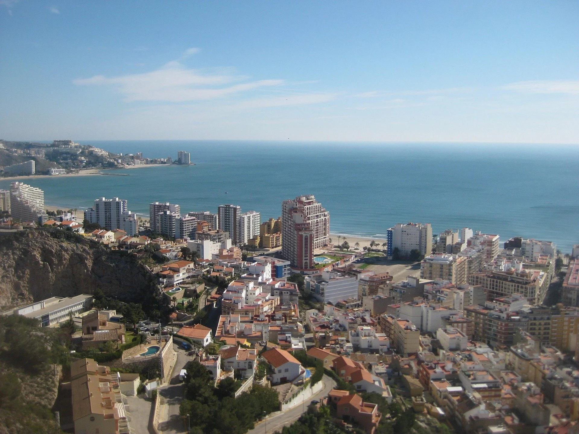 Vista aérea de Cullera, ciudad costera de Valencia, España, con edificios altos y casas, junto a la playa y el mar Mediterráneo en un día soleado.