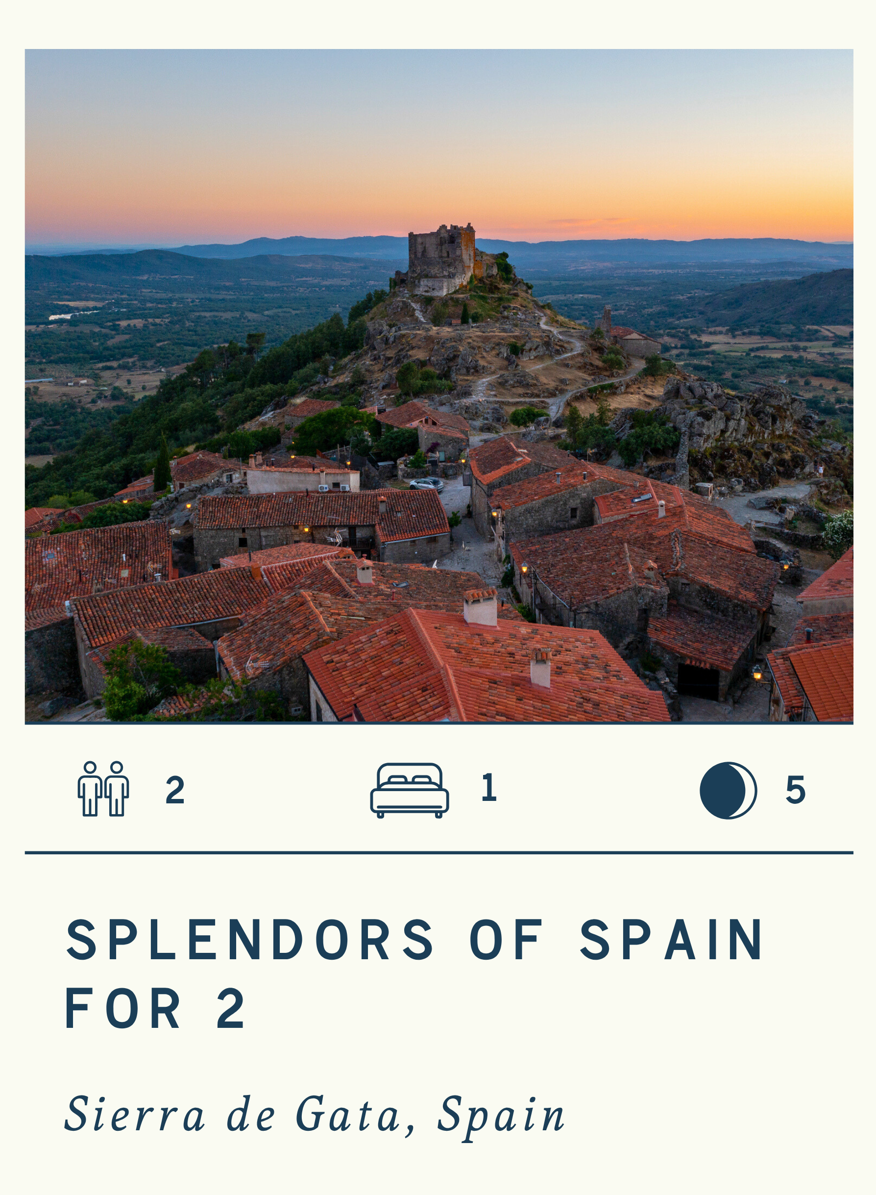 Scenic view of a medieval town with red-tiled roofs in Spain, with a castle on a hill and rolling mountains in the background at sunset.